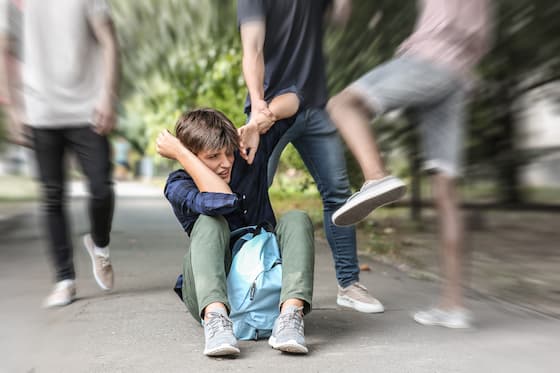 Puber jongen op de grond wordt door pester en meelopers geschopt